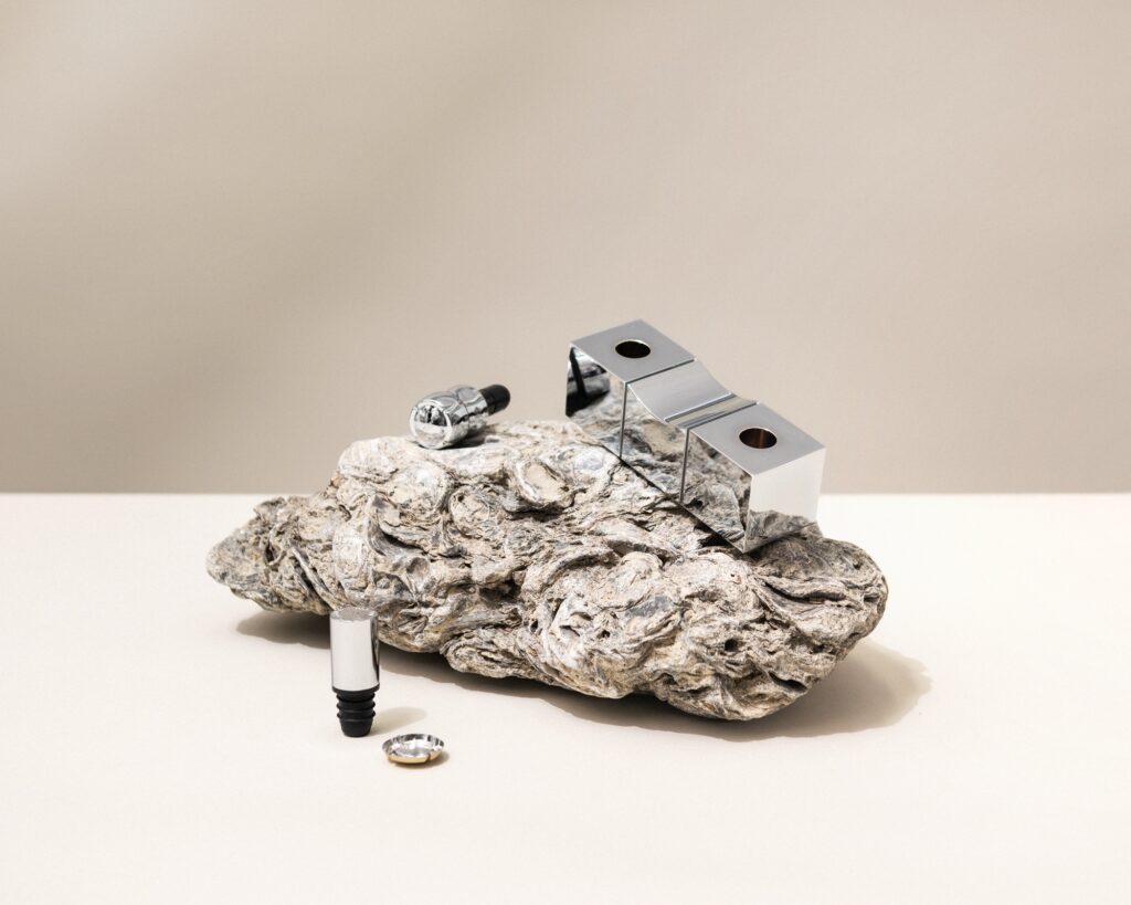 Eine Basis, die zugleich praktisch und skulptural ist. Gefertigt aus massivem Aluminium. Handbearbeitet mit silbernen Akzenten.