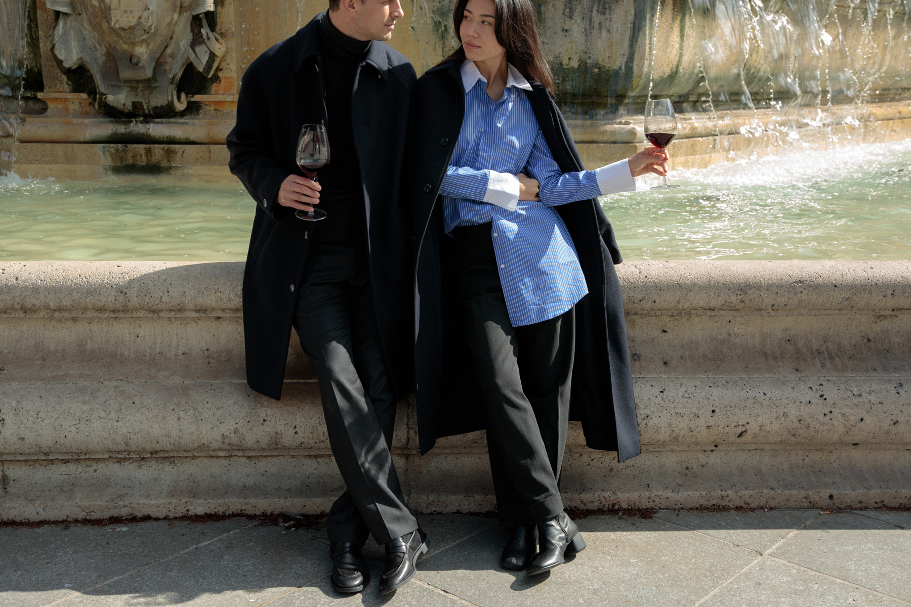 Deux personnes dégustant un verre de vin devant la fontaine Saint-Sulpice à Paris.