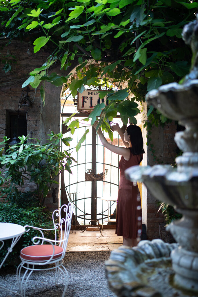 In a garden, a woman pruning the branches of a shrub with her Felco pruning shears.